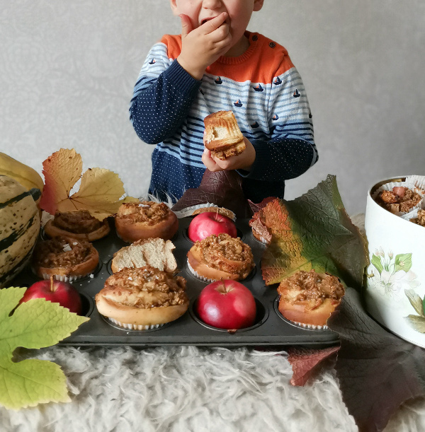 Kuvassa on lapsi, joka haukkaa suurta muffinssia. Lapsen edessä on muffinssipelti, jonka joka toisessa kolossa on punainen omena ja joka toisessa muffinssi.