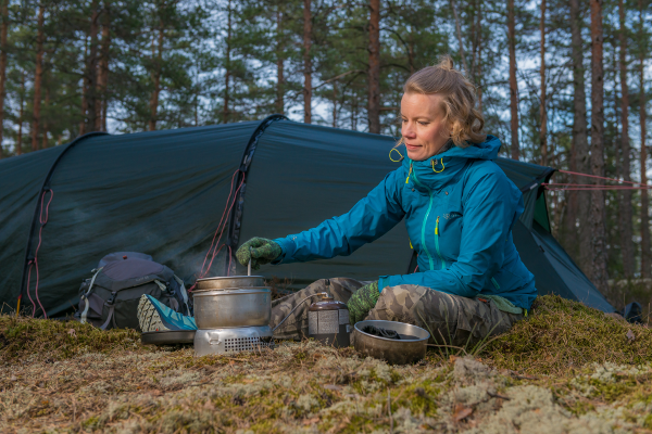 Kuvassa Mia valmistaa ruokaa trangialla teltan edessä.