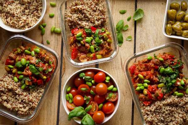Kuvassa on kolmessa eväsrasiassa Beanit-pataa ja kvinoaa ja kulhossa tuoreita vihanneksia.